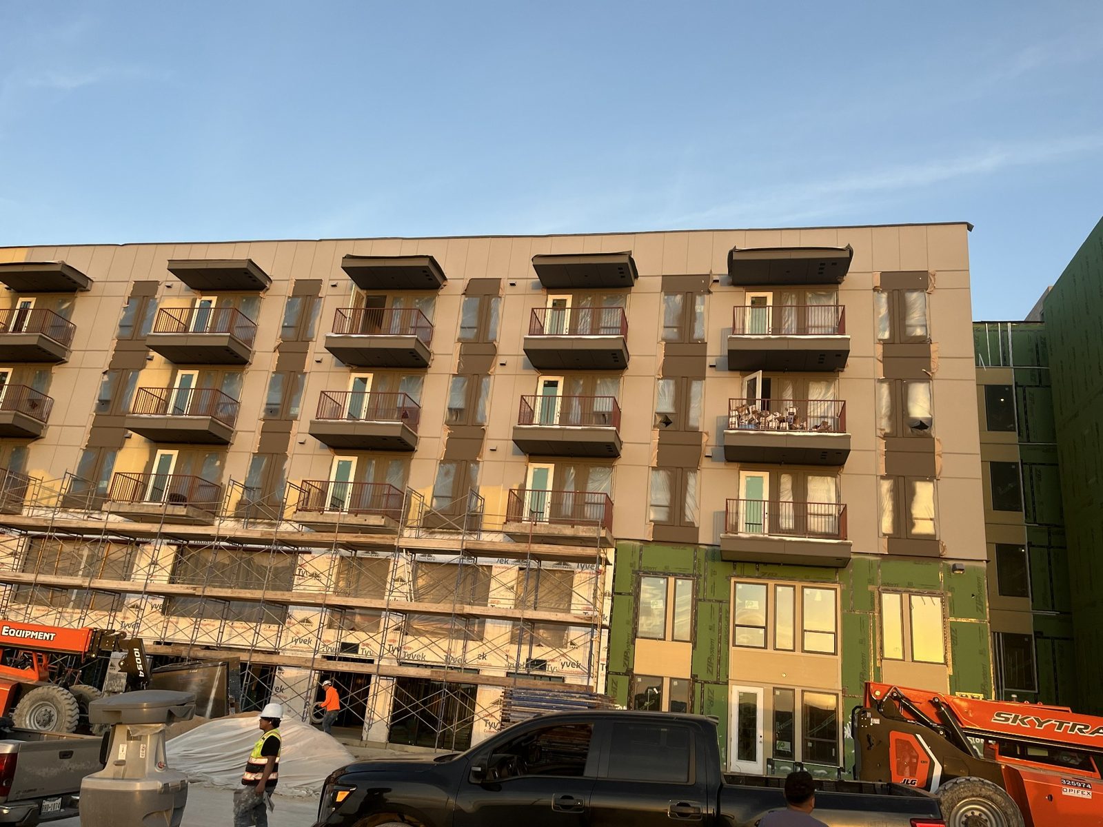 Multifamily exterior painting in progress with lifts and scaffolding
